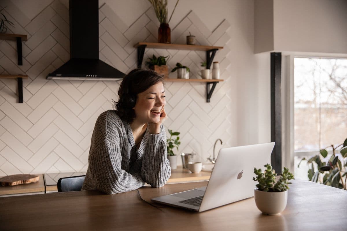 A woman laughing during a warm video visit at her kitchen table